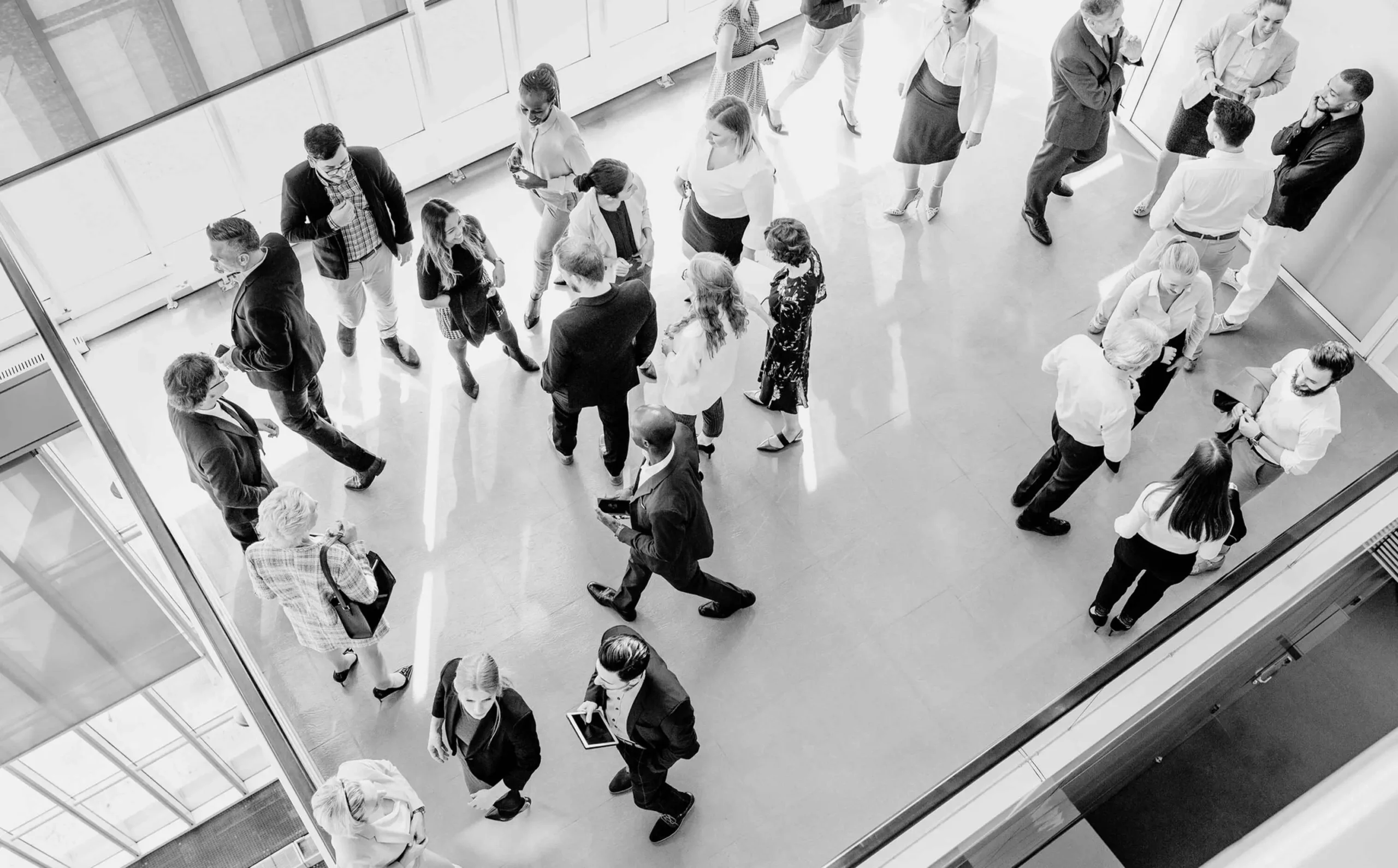 Overhead view of conference attendees mingling and networking in a bright hall.